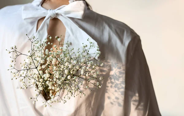 Mujer joven con hermosas flores en blusa sobre fondo claro, vista trasera — Foto de Stock