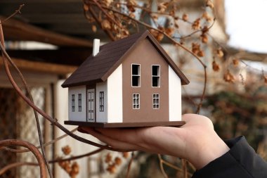 Dışarıda ev modeli tutan kadın. Deprem kavramı