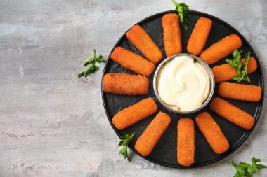 Gri masada lezzetli mozzarella çubukları ve sos ile plaka