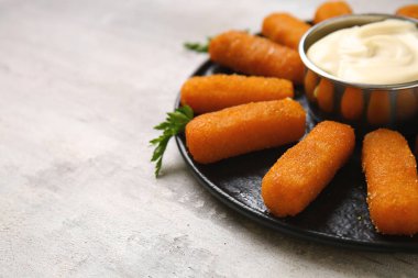 Gri masada lezzetli mozzarella çubukları ve sos ile plaka