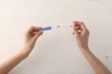 Beyaz ahşap arka planda gebelik testi ile kadın eller