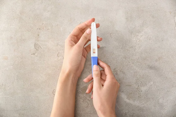 Female hands with pregnancy test on grey background — Stock Photo, Image