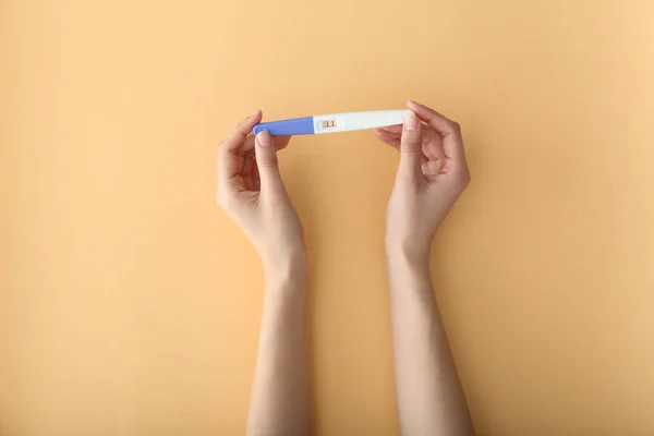Kobiece ręce z testu ciążowego na kolorowym tle — Zdjęcie stockowe