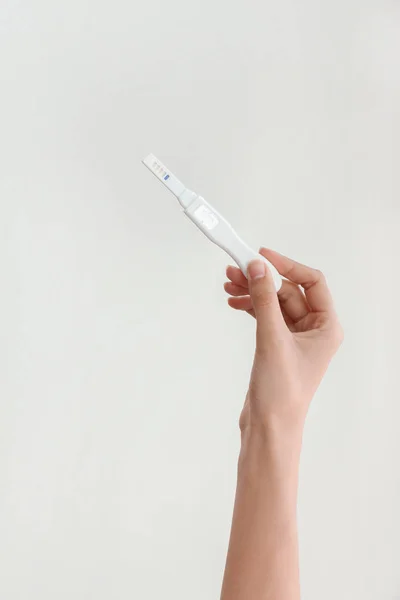 女性手与怀孕测试在轻的背景 — 图库照片