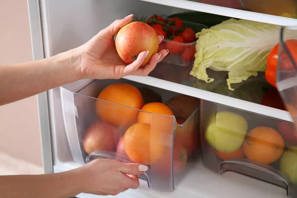Frau holt Apfel aus Kühlschrank — Stockfoto