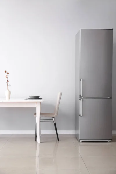 Modern fridge and served table in kitchen — Stock Photo, Image