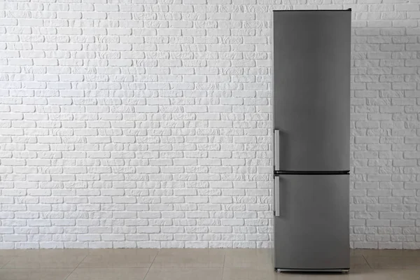 Modern fridge near white brick wall — Stock Photo, Image