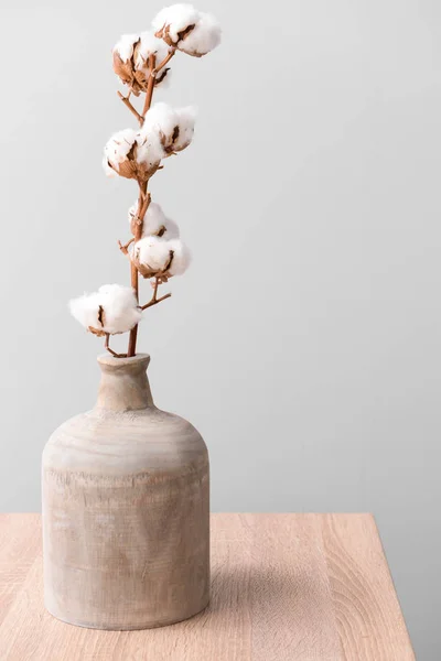 Cotton flowers in vase on table against light background — Stock Photo, Image