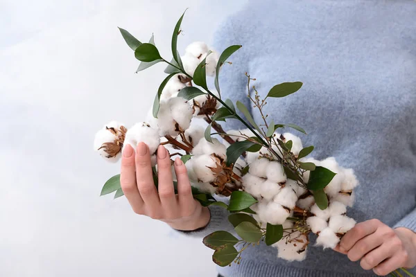 Woman holding floral composition with cotton flowers on light background — Stock Photo, Image