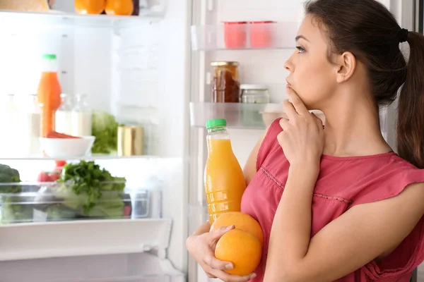 Mujer sacando comida de la nevera en casa —  Fotos de Stock