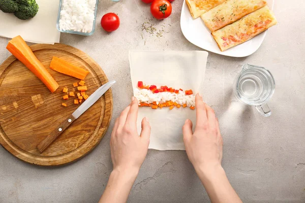 Gri masada lezzetli bahar rulo hazırlanıyor kadın