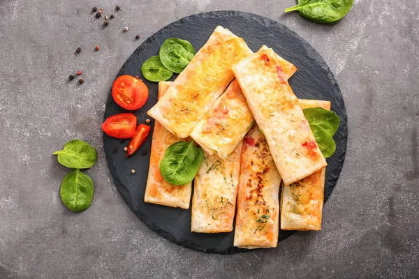 Assiette d'ardoise avec de savoureux rouleaux de printemps frits sur fond gris — Photo