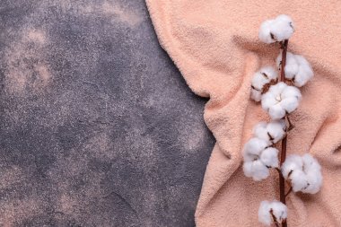 Gri arka planda yumuşak havluyla pamuklu çiçekler