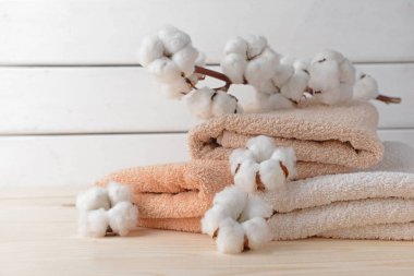 Cotton flowers with soft towels on wooden table