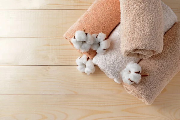 Cotton flowers with soft towels on wooden table — Stock Photo, Image