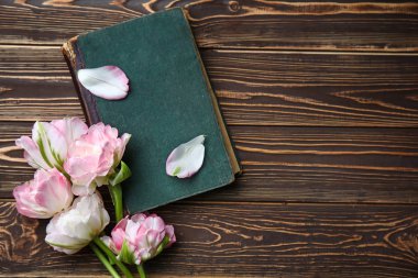 Ahşap arka planda güzel laleler ve kitap