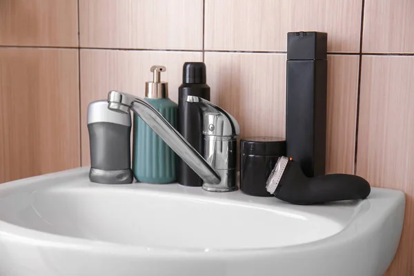 Electric shaver with cosmetics on sink in bathroom — Stock Photo, Image