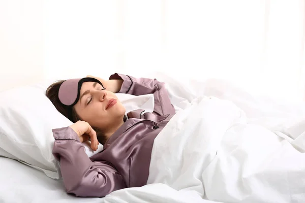 Jovem com máscara de sono na cama — Fotografia de Stock