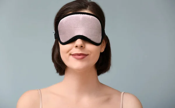 Young woman with sleep mask on color background — Stock Photo, Image