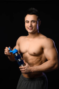 Karanlık arka planda protein sallama ile sportif adam