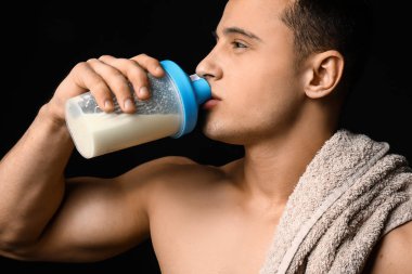Karanlık arka planda sportif adam içme protein shake
