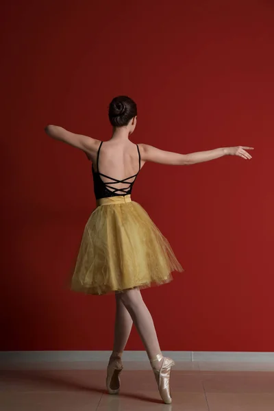 Beautiful young ballerina against color wall — Stock Photo, Image