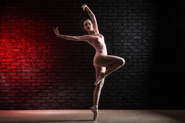 Mooie jonge ballerina tegen donkere muur — Stockfoto