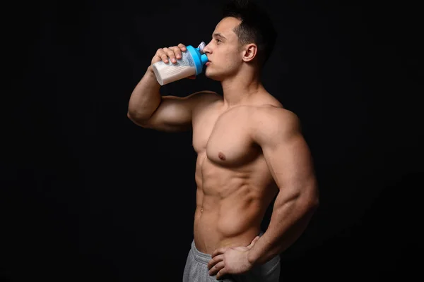 Sporty man with protein shake on dark background — Stock Photo, Image