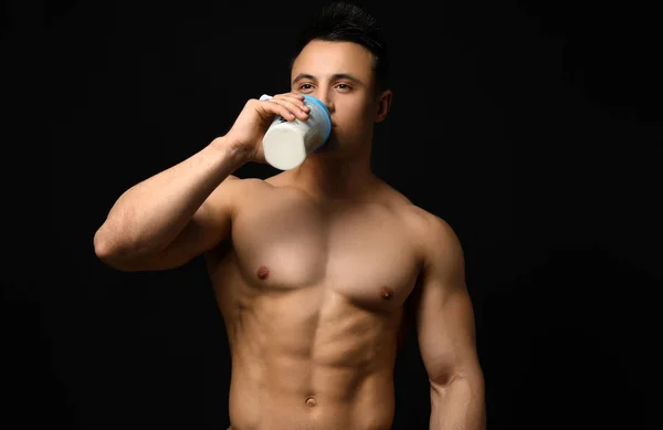 Sportig man dricker protein skaka på mörk bakgrund — Stockfoto