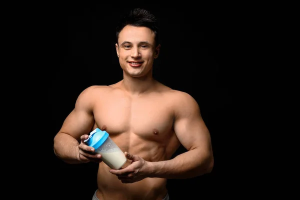 Sporty man with protein shake on dark background — Stock Photo, Image