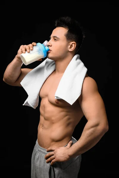 Sporty man drinking protein shake on dark background — Stock Photo, Image