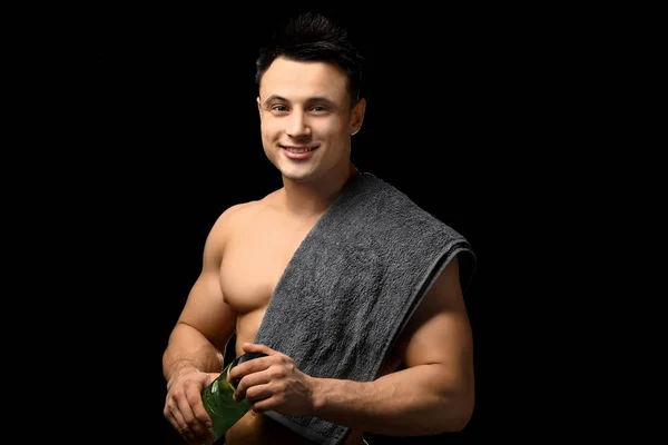 Sportieve man met fles water op donkere achtergrond — Stockfoto