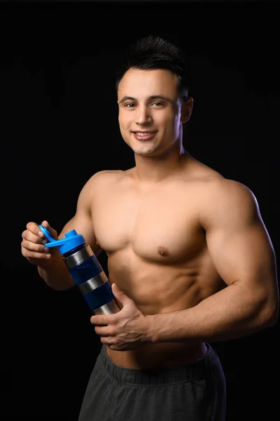 Sportig man med proteinshake på mörk bakgrund — Stockfoto