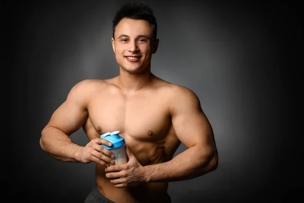 Sporty man with protein shake on dark background — Stock Photo, Image