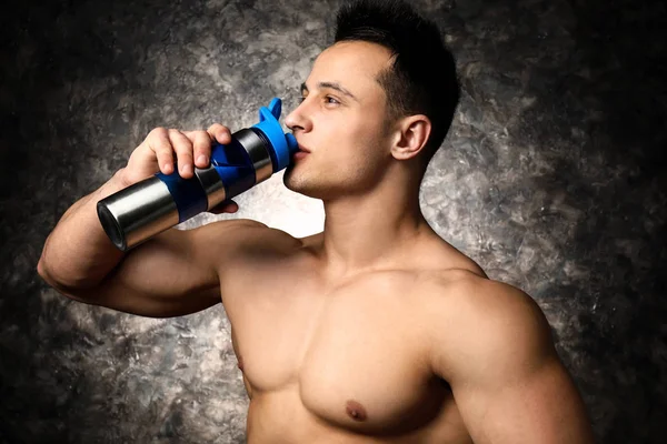 Sporty man drinking protein shake on dark background — Stock Photo, Image