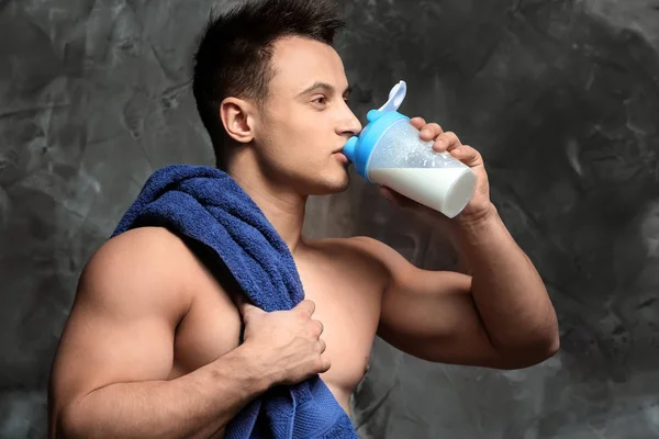 Sporty man drinking protein shake on grunge background — Stock Photo, Image
