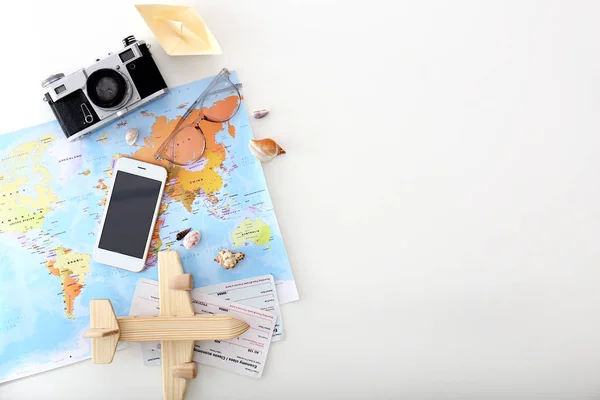 Carte du monde, avion jouet, téléphone, appareil photo, billets et bateau en papier sur fond blanc. Concept de voyage — Photo