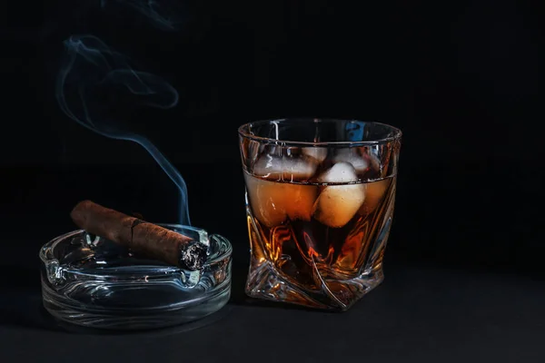 Glass of cold whiskey with cigar on dark background — Stock Photo, Image