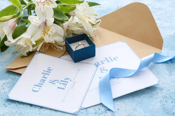 Huwelijksuitnodigingen, ring en bloemen op tafel — Stockfoto