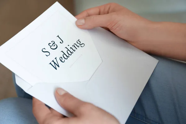 Жінка тримає конверт із запрошенням на весілля, крупним планом — стокове фото