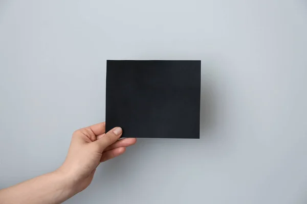 Female hand with blank invitation card on light background — Stock Photo, Image