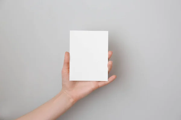 Female hand with blank invitation card on light background — Stock Photo, Image