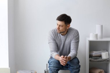 Klozet üzerinde evde oturan adam