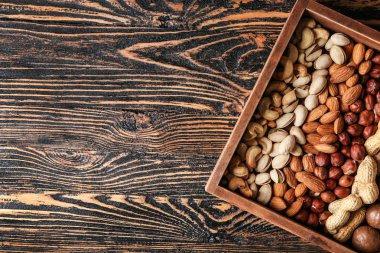 Ahşap masada farklı lezzetli fındık ile kutu