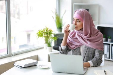 Ofiste laptop üzerinde çalışan Müslüman kadın