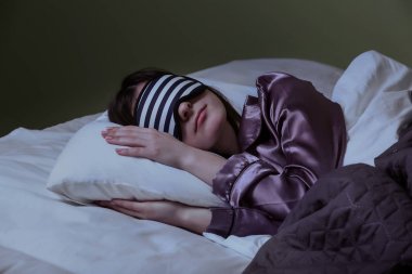 Gece yatakta uyku maskesi ile genç kadın