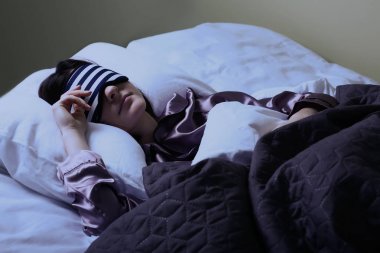 Gece yatakta uyku maskesi ile genç kadın