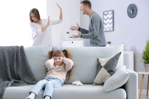 Грустная маленькая девочка закрывает уши, пока ее родители спорят дома — стоковое фото