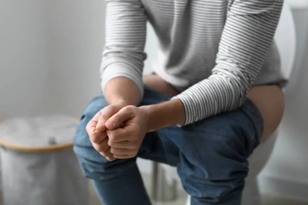 Man sitting on toilet bowl at home — Stock Photo, Image