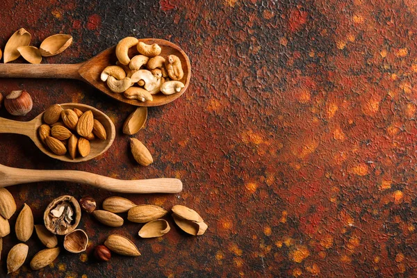 Ложки с различными вкусными орехами на цветном фоне — стоковое фото